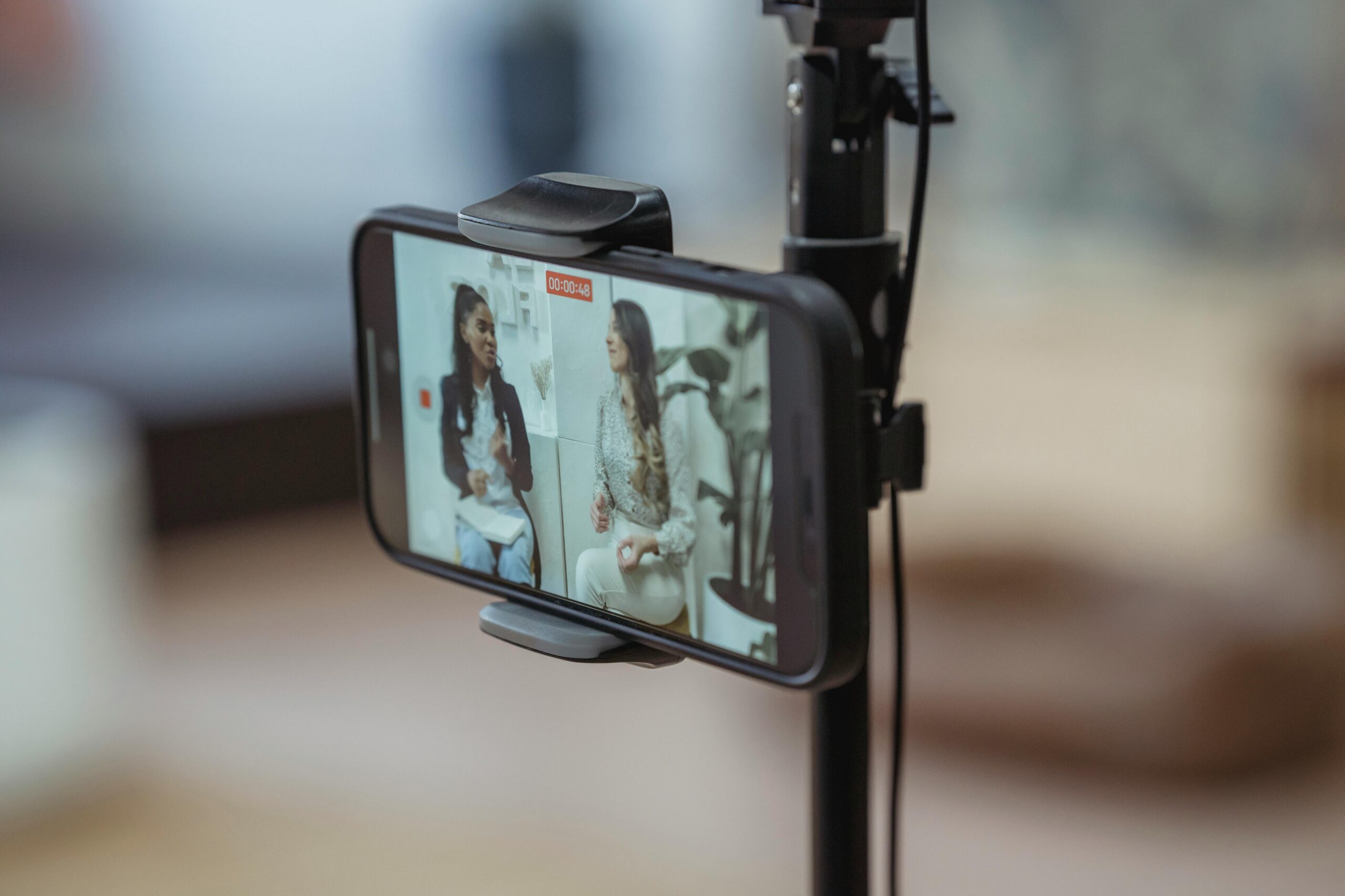 A smartphone filming two women talking side-by-side.