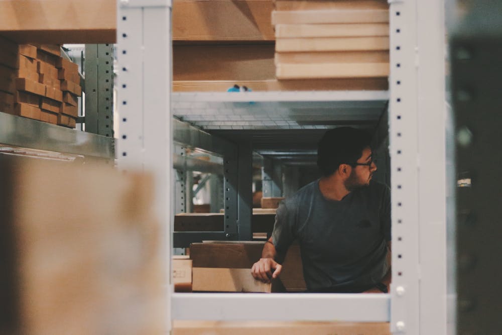 Man looking through shelves in a warehouse.