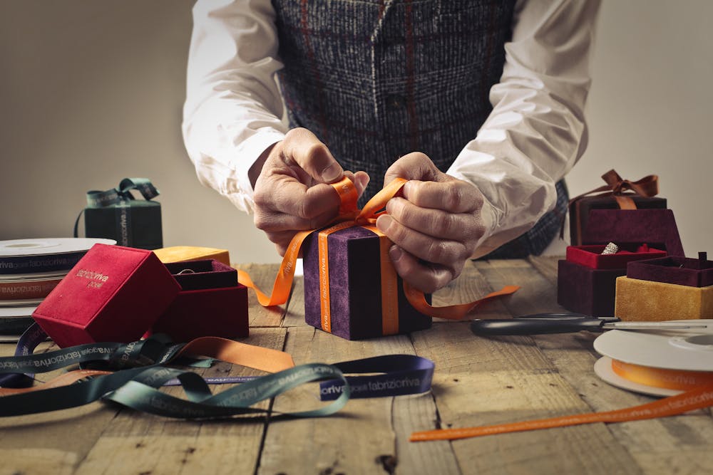 Person tying a bow on a gift wrapped item