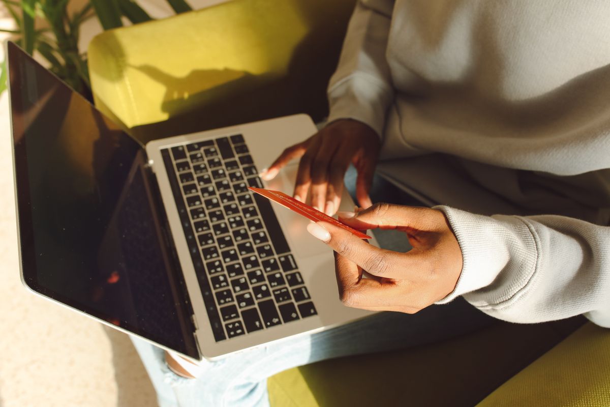 Customer holding a credit card while signing up to an online subscription on a laptop
