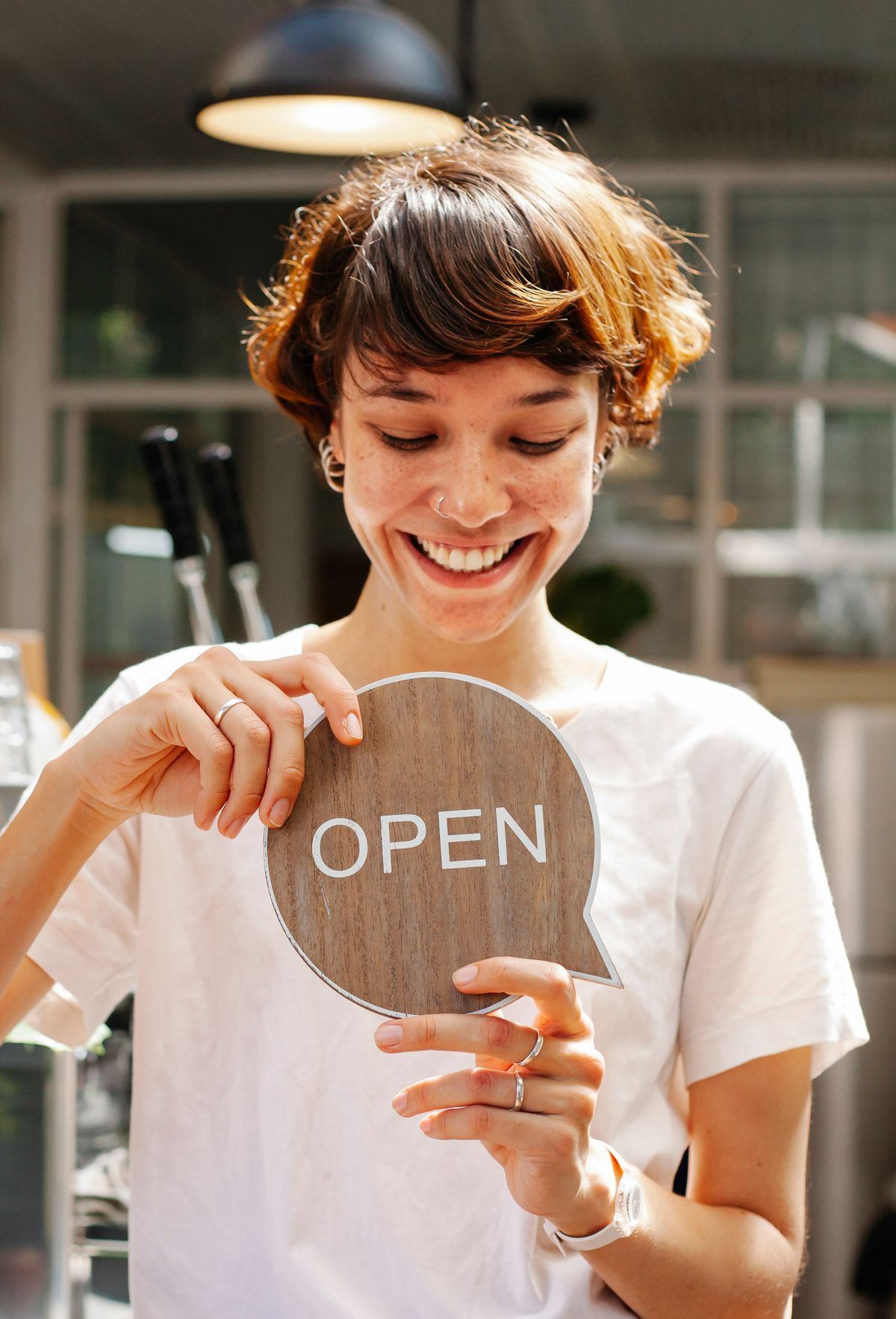 Small business owner holding an open sign in her shop window, a brand worth protecting with a trade mark